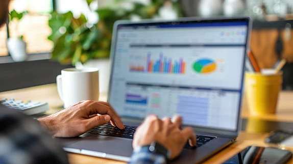 Hände am Laptop mit Analytics-Dashboard – KPIs, Conversions und Kanäle im Bericht.