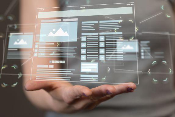 Hand hält Website-Layout als HUD – Webdesign und SEO greifen zusammen: Struktur, Content-Tiefe und interne Verlinkung für bessere Conversion.